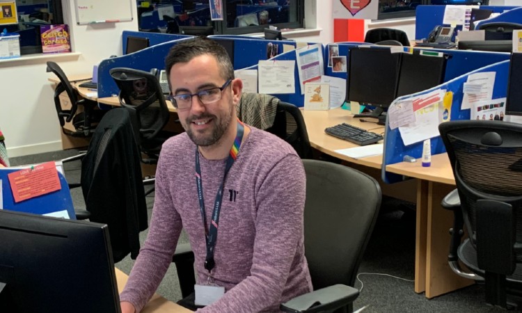 Dean Walker, Help Team Leader at AXA, sat at his desk in the office